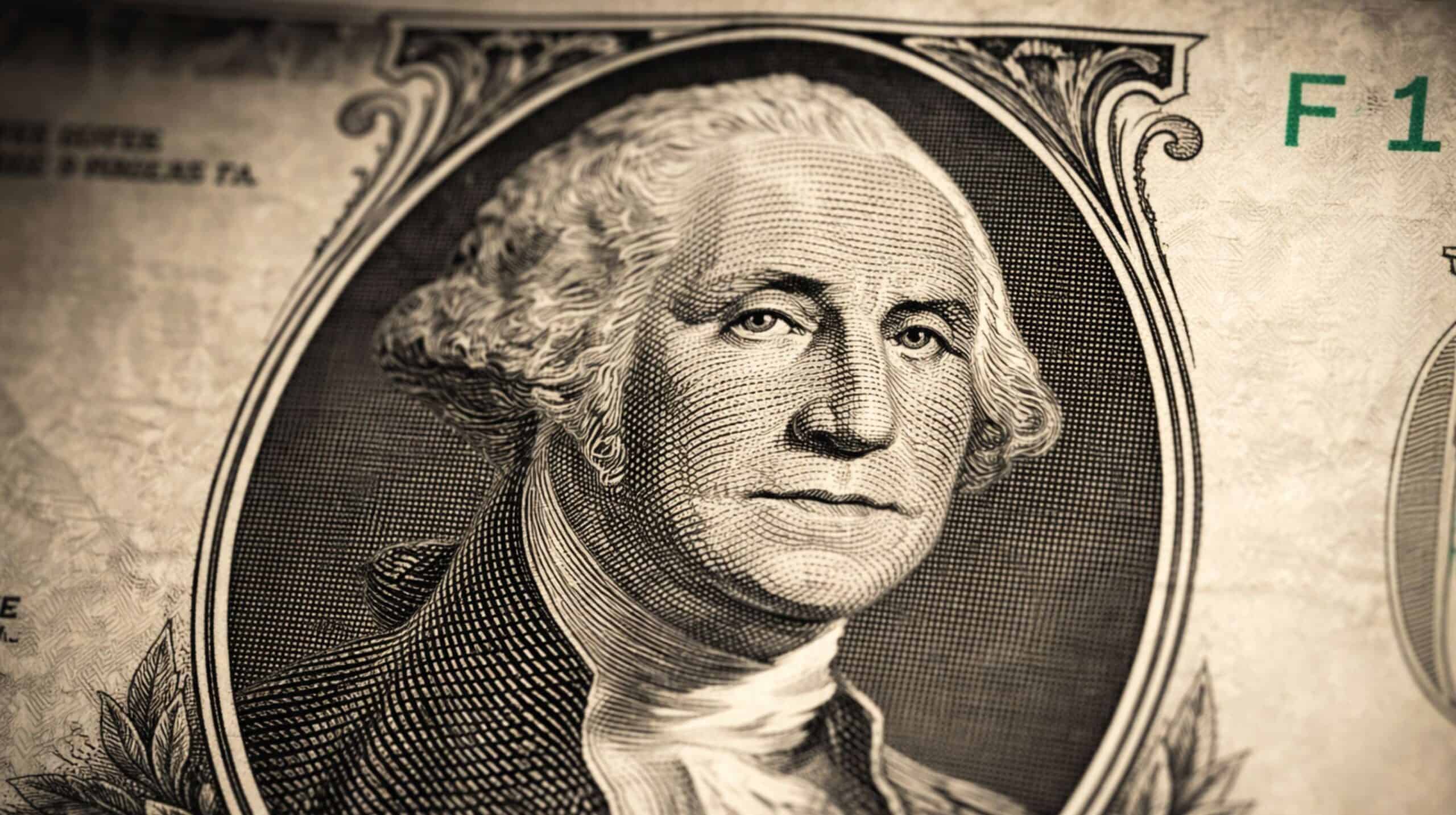 Close-up de uma nota de um dólar americano, com foco no retrato de George Washington, mostrando detalhes das linhas e da textura do papel-moeda.