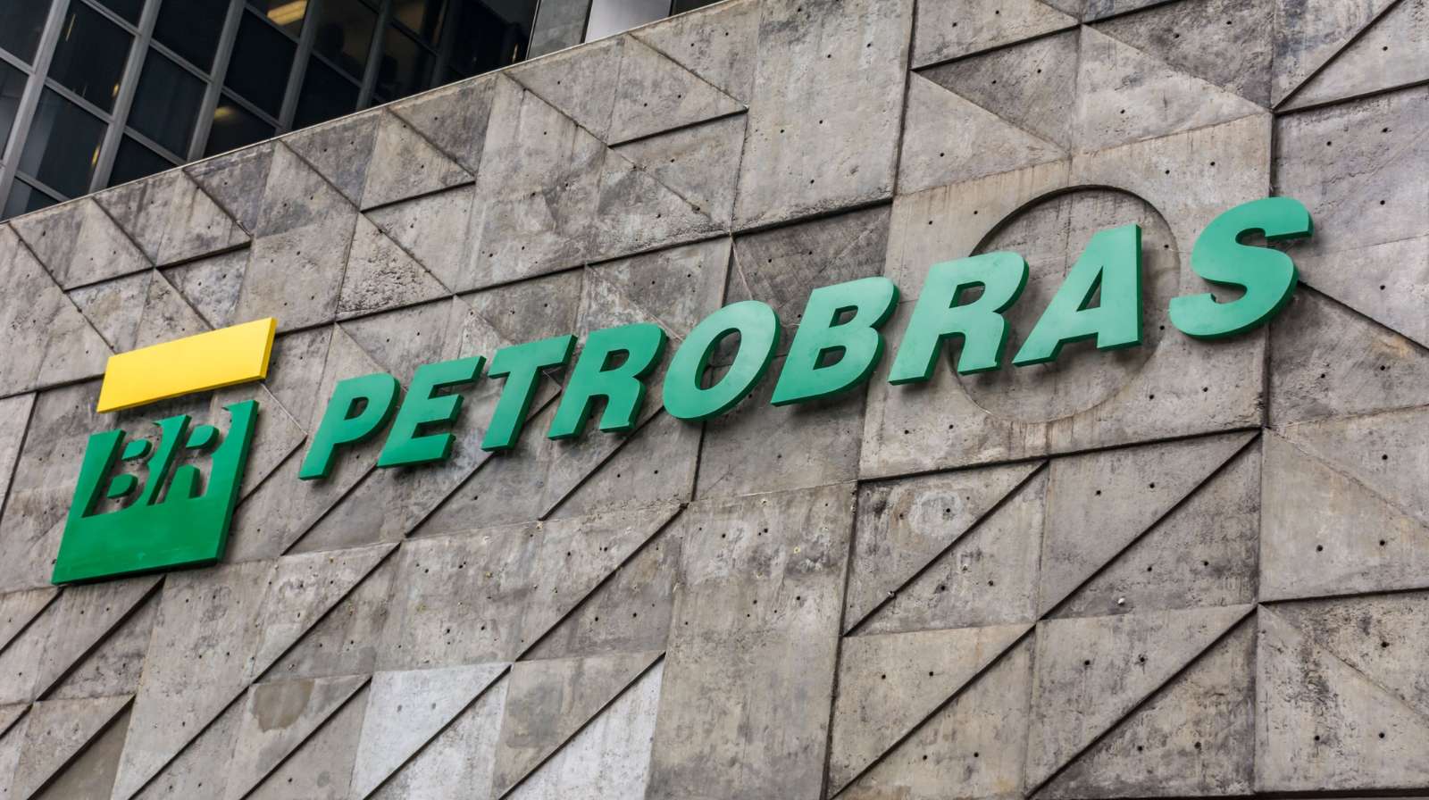 Fachada da Petrobras com logotipo verde e amarelo em prédio de concreto no centro urbano.