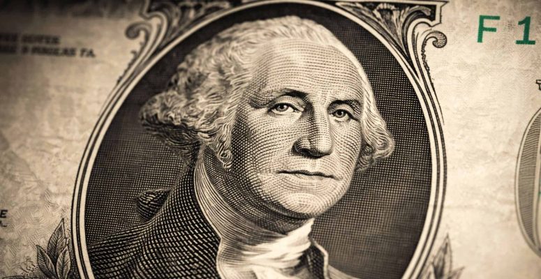 Close-up de uma nota de um dólar americano, com foco no retrato de George Washington, mostrando detalhes das linhas e da textura do papel-moeda.
