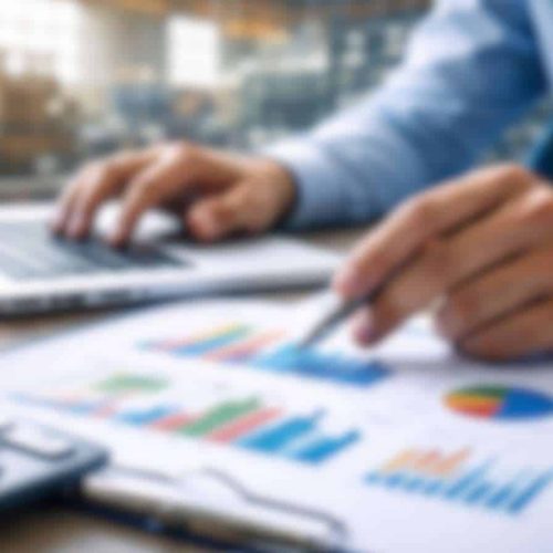 Analista econômico revisando relatórios industriais em laptop com gráficos financeiros, representando a análise do IPP na indústria.