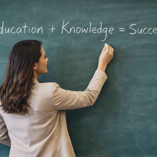 “Professora escrevendo em quadro verde durante aula em sala, representando ensino e educação”