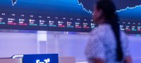 b3Pessoa olhando telão com gráficos e dados financeiros do Banco do Brasil no 1T26.