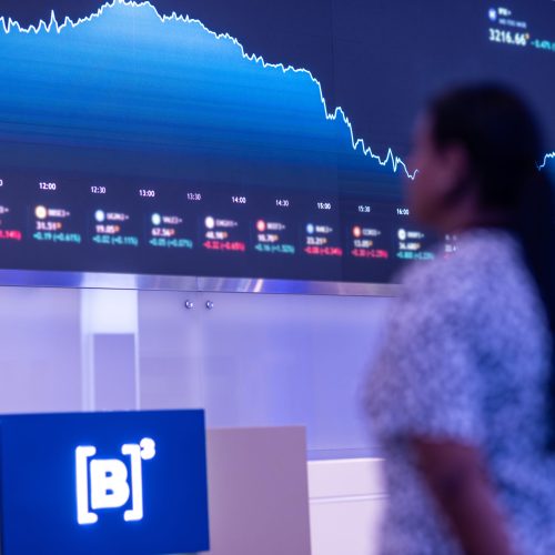 b3Pessoa olhando telão com gráficos e dados financeiros do Banco do Brasil no 1T26.