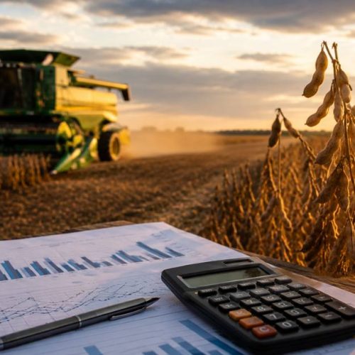 Banco do Brasil agro — plantação de soja ao pôr do sol com colheitadeira ao fundo e documentos financeiros sobre mesa, representando a crise no agronegócio e o impacto nos resultados do banco