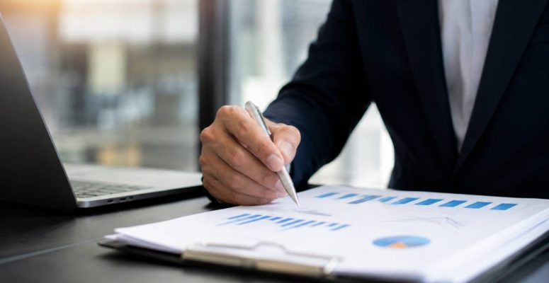 Executivo analisa gráficos de inflação e indicadores econômicos durante divulgação do Boletim Focus em escritório corporativo moderno.
