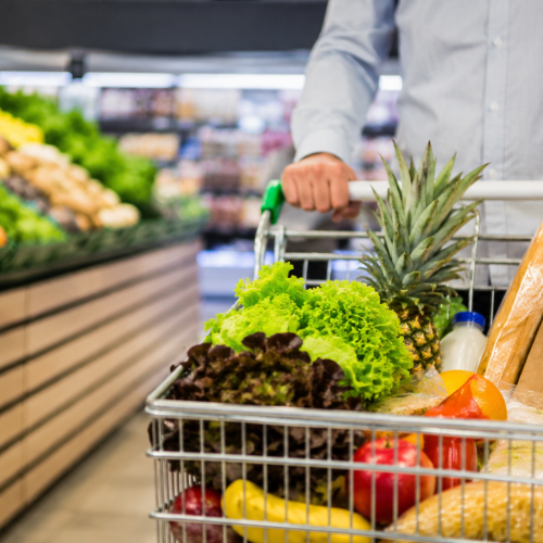 Consumidor faz compras em supermercado com carrinho cheio de alimentos durante alta do IPCA acumulado em 12 meses no Brasil.